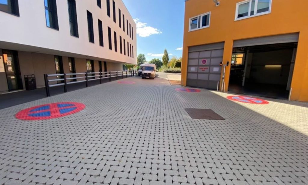 Marquage de pictogrammes "stationnement interdit" en thermoplastique sur du sol en klinkers